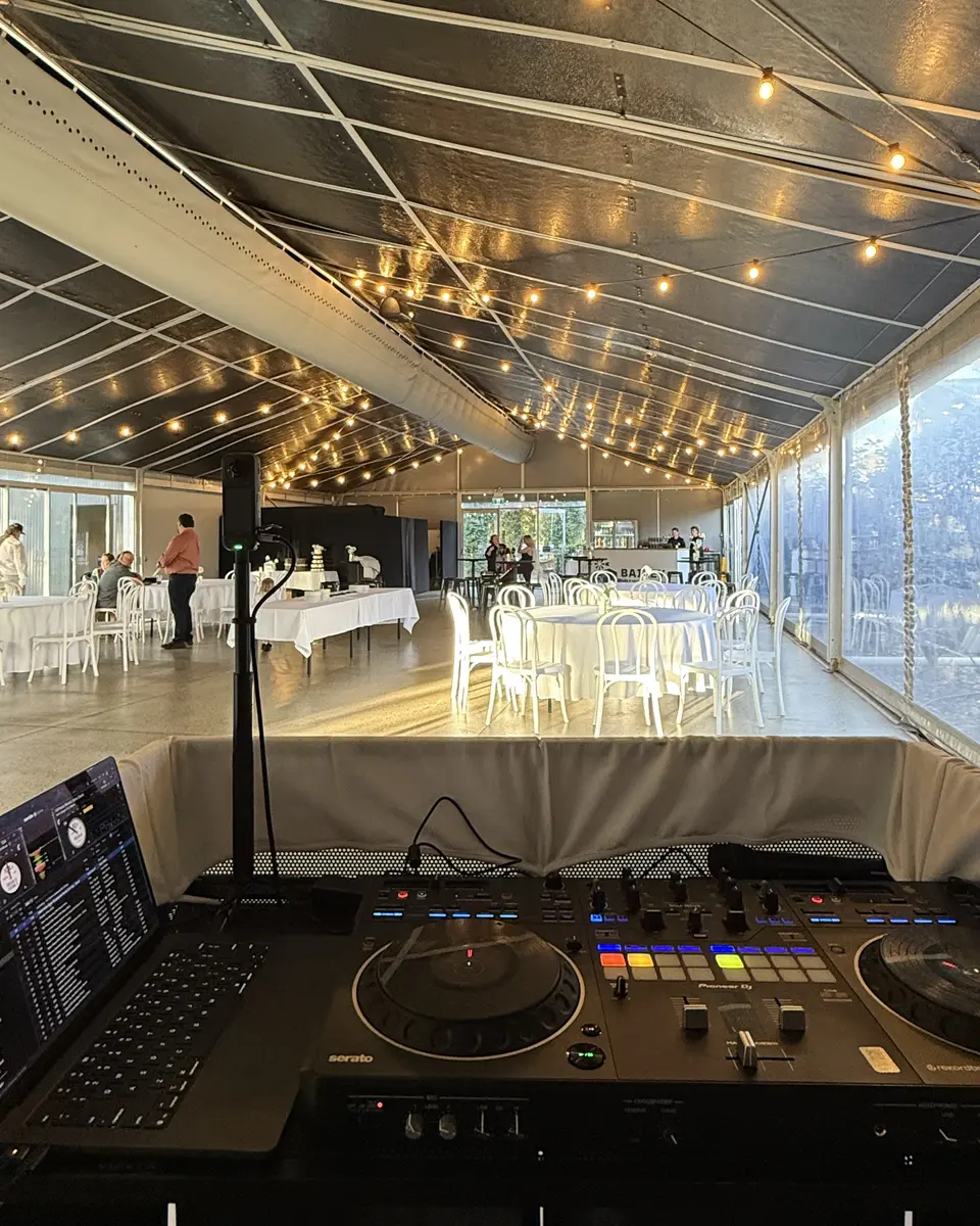 View from the Certified Entertainment DJ booth across a wedding reception set under festoon lights